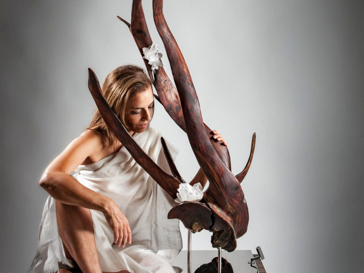Sculptor Dorit Schwartz seated beside one of her wood and crystal sculptures