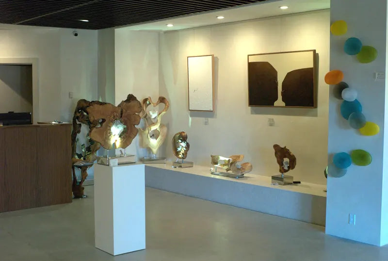 Wood and crystal sculptures on a low platform beside paintings and colored glass at GAIA Sun Valley